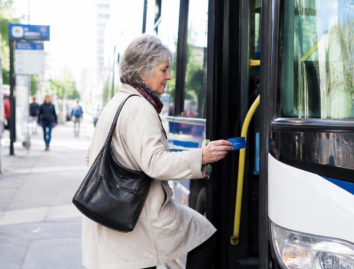 Senior woman tapping a transit card while boarding a bus